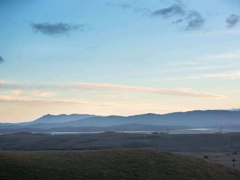 Sunset view of distant mountains and a valley with wetlands