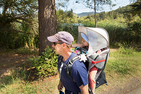 Father hiking with child in backpack