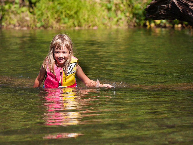 girl wearing a life jacket swims in river