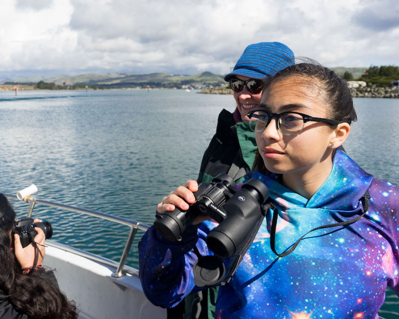 girl holding binoculars looking on deck