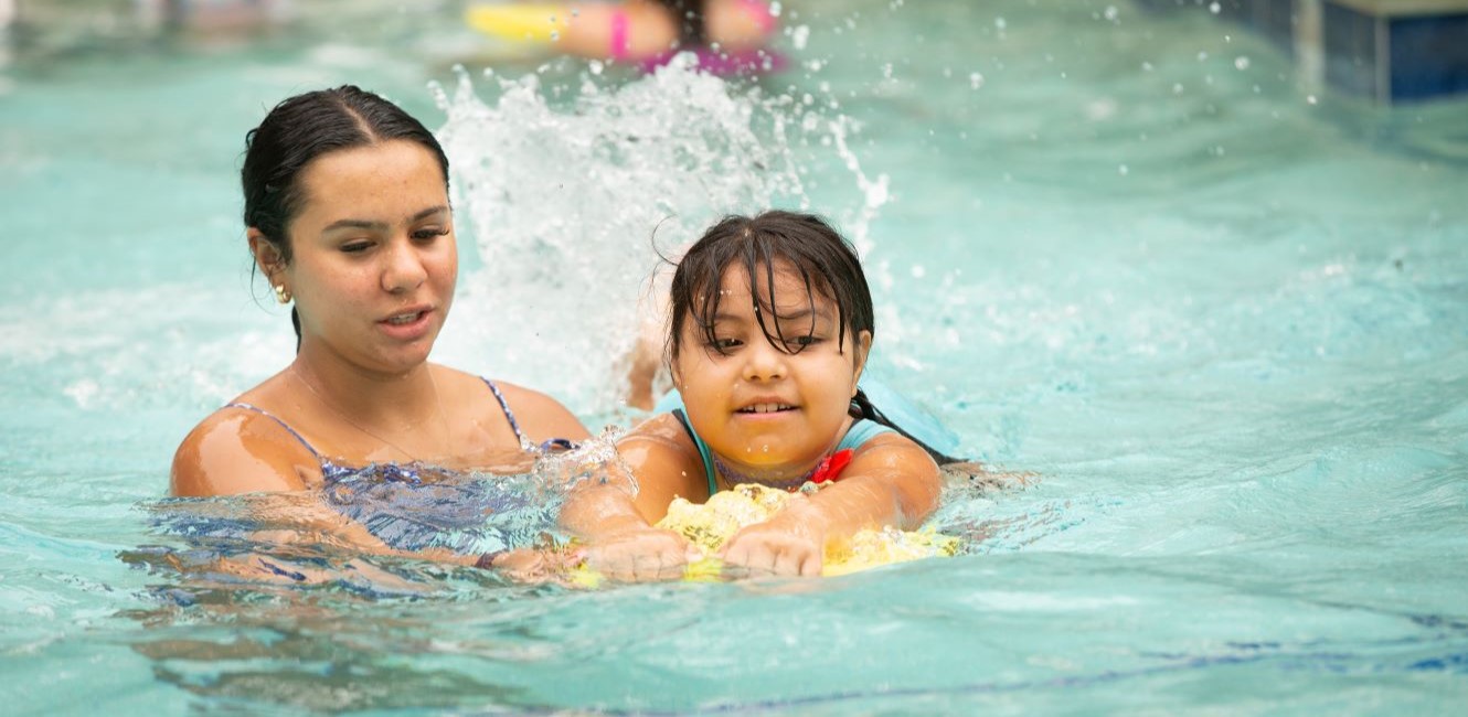 swim instructor teaching a young girl to swim